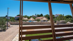 A wooden pergola structure with a view of a pool area and buildings in the background. - Mobile Home Banovi Dvori II (Tisno)