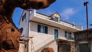 A two-story building with a balcony, a staircase, and a stone facade. - House Natalija (Primosten)