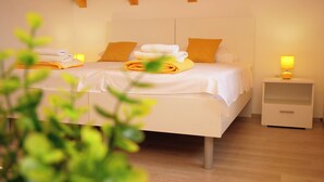 A bedroom with two beds, wooden ceiling beams, a bedside table with a lamp, and a small drawer. - House Natalija (Primosten)