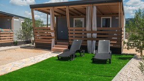 A covered outdoor area with two lounge chairs and a wooden fence. - Mobile Home Banovi Dvori III (Tisno)