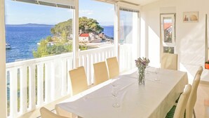 A dining area with a table set for six, overlooking a scenic coastal view. - Apartment Sammy (Sali)