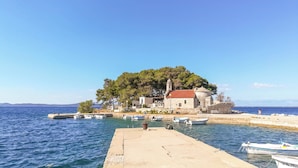 A coastal village with a prominent church, boats docked at the pier, and a clear blue sky. - Apartment Sammy (Sali)