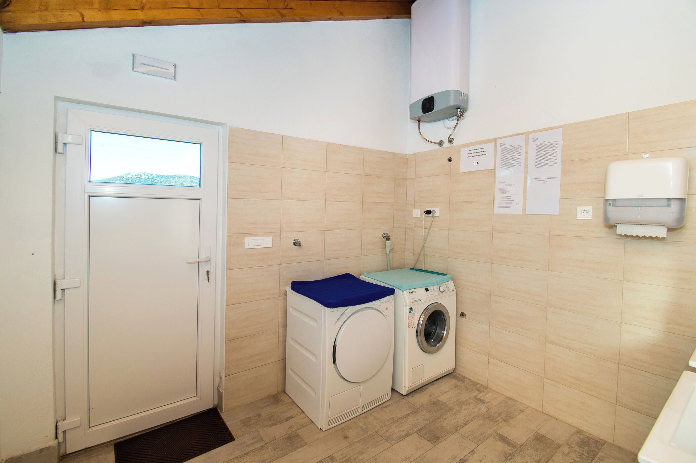 A laundry room with a washing machine and dryer, a door with a window, and a wall-mounted air conditioning unit.