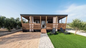 A modern cabin with a covered porch, stone pathway, and green lawn. - Mobile Home Banovi Dvori IV (Tisno)
