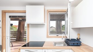 A modern kitchen with white cabinets, a black countertop, a built-in oven, and a window with a view of the outdoors. - Mobile Home Banovi Dvori IV (Tisno)