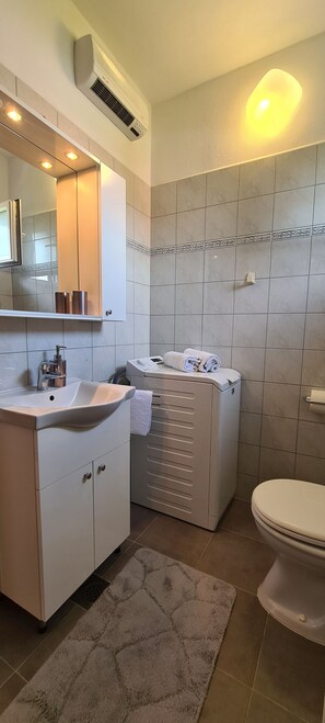 A modern bathroom with a white sink, mirror, and toilet. - Apartment Sea View (Jelsa)