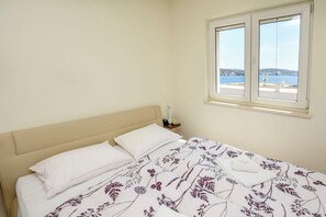 A bed with a floral bedspread, a white pillow, and a nightstand with a lamp. - Apartment Slavica (Rogoznica)