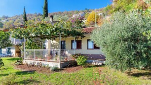 A house with a covered porch, a garden, and a hillside in the background. - House Cvetko (Lovran)