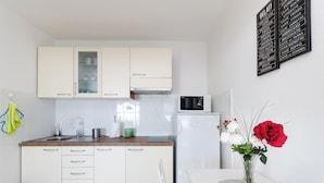 A modern kitchen with white cabinets, a microwave, and a vase with flowers on the counter. - House Cvetko (Lovran)