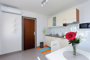 Een moderne keuken met witte kastjes, een magnetron, en een vaas met bloemen op tafel.