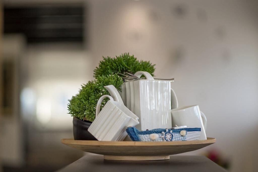A tray with white ceramic mugs and a small potted plant on a wooden table.