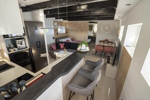 A modern kitchen with a central island, bar stools, and a dining area with a table and chairs. - Apartment Royal Studio (Rijeka)