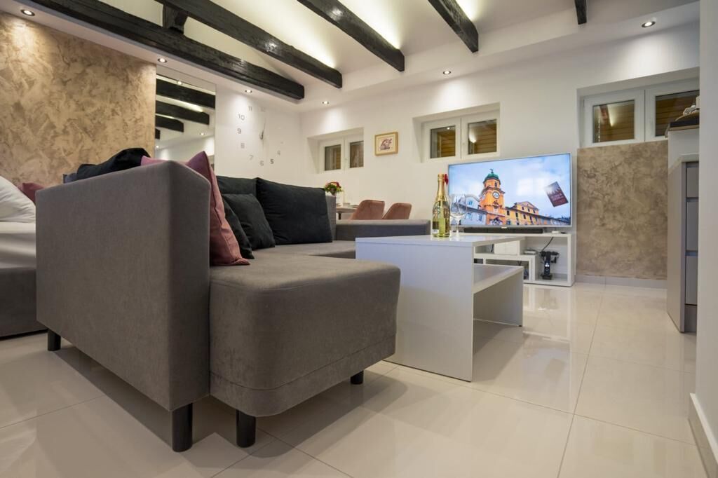 A modern living room with a grey sofa, a flat-screen TV, and a small coffee table.