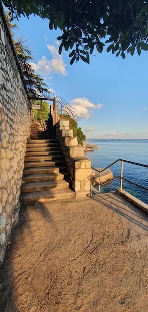 A stone staircase leading to a coastal area with a clear view of the sea. - Apartment Royal Studio (Rijeka)