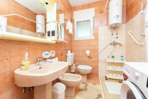 Ein modernes Badezimmer mit Waschbecken, Bidet, Toilette und Duschbereich.