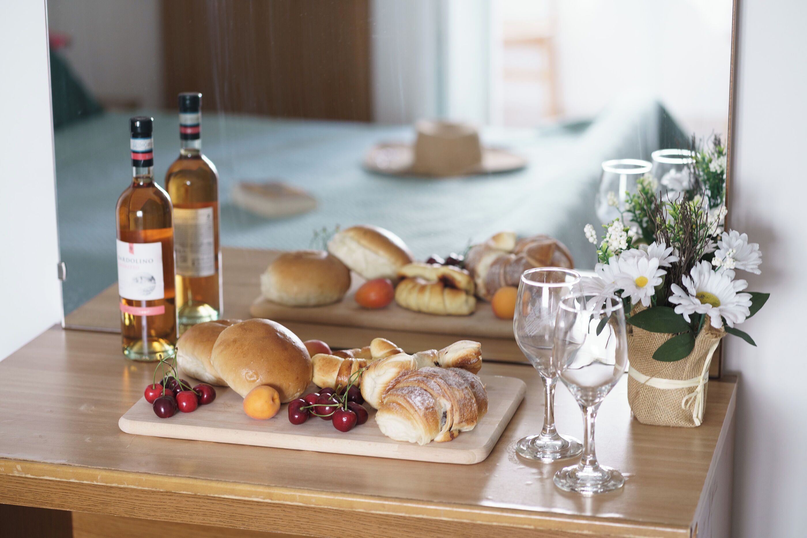Een houten tafel met gebak, een fles drank en een bloemenvaas.