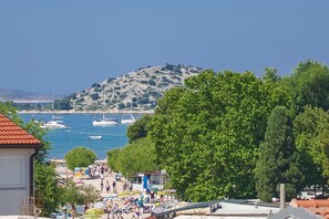 Una cittadina costiera con spiaggia, barche e una collina sullo sfondo.
