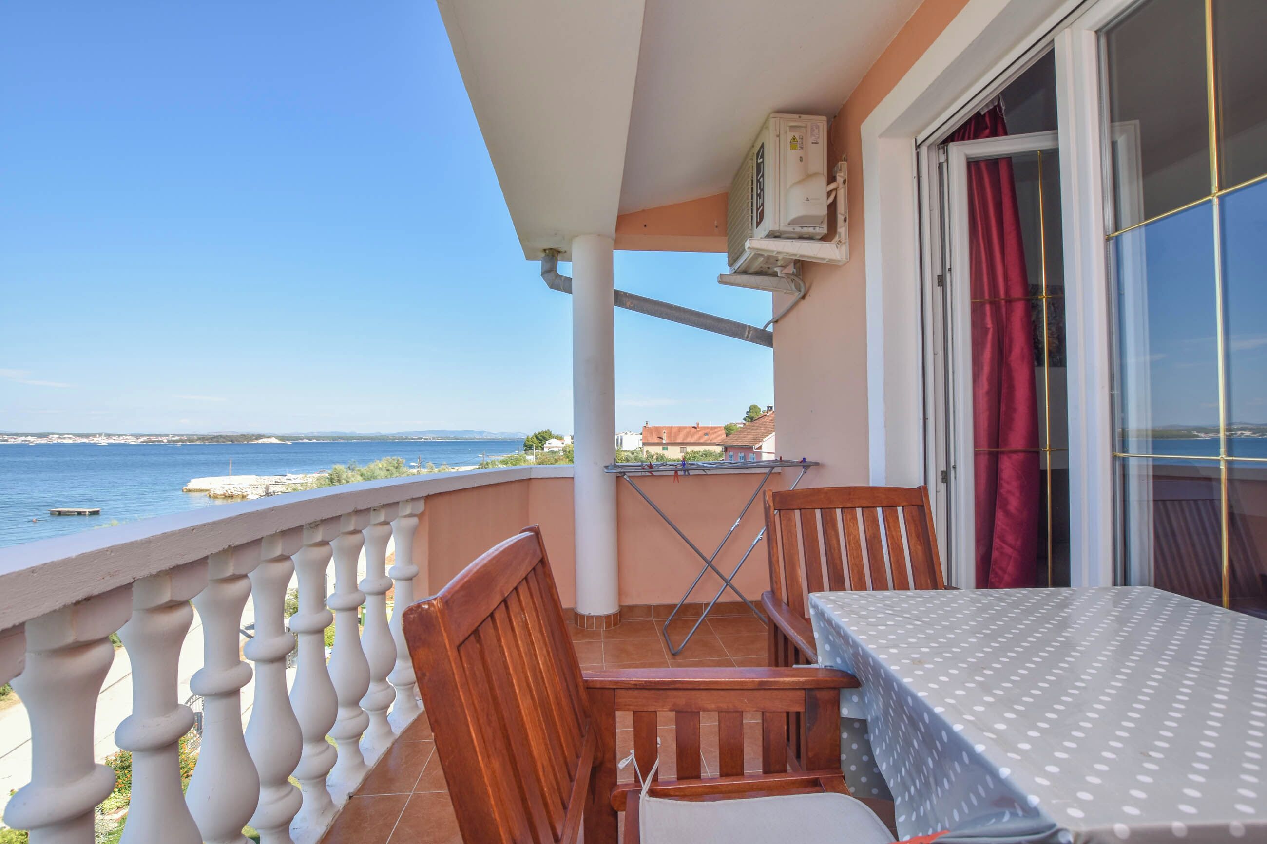 A balcony with a table and chairs, overlooking a body of water.