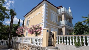 A two-story villa with a balcony, a stone wall, and a gate. - Apartments Villa Anna (Opatija)