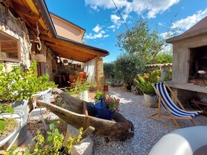 A courtyard with a stone wall, potted plants, a wooden bench, and a chair. - House Rustic Heaven (Novi Vinodolski)