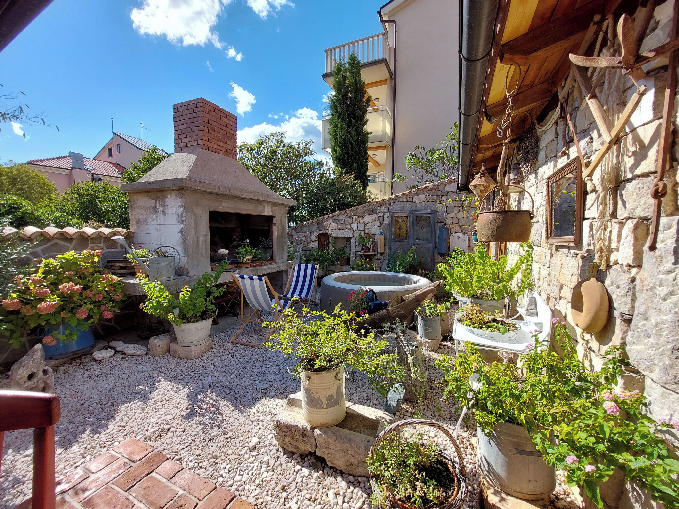 A courtyard with a barbecue area, outdoor seating, and potted plants.