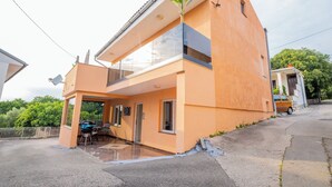 Een modern huis met twee verdiepingen, een balkon, een garage en een patio met tuinmeubilair.