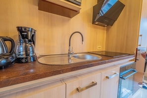 A modern kitchen with a built-in coffee maker, stainless steel sink, and a sleek oven. - House Lady 1 (Novi Vinodolski)