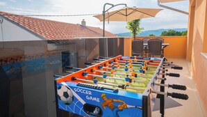 Een tafelvoetbaltafel met een voetbalthema, op een balkon met uitzicht op bergen.