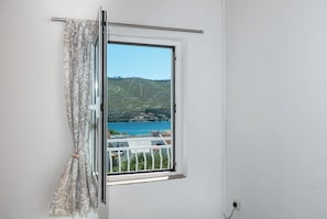 Ein Fenster mit Blick auf ein Gewässer und Hügel.