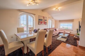 A modern living room with a dining area, large windows, and a view of the outdoors. - Apartments Lady 2 (Novi Vinodolski)