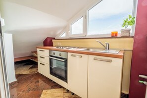 Uma cozinha compacta com forno embutido, pia e janela sobre a bancada.