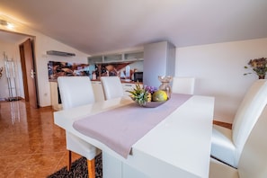 A modern dining area with a white table, cushioned chairs, and a decorative centerpiece. - Apartments Lady 2 (Novi Vinodolski)