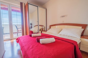 A hotel room with a large bed, a sliding glass door to a balcony, and a wooden nightstand. - Apartments Lady 2 (Novi Vinodolski)