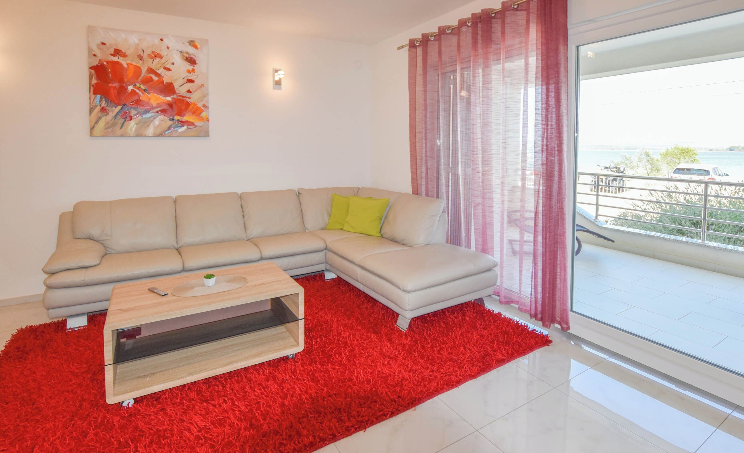 A modern living room with a beige sectional sofa, a red shag rug, and a wooden coffee table.