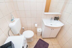 A small bathroom with a toilet, sink, and a mirror above the sink. - Apartment Monika (Vodice)