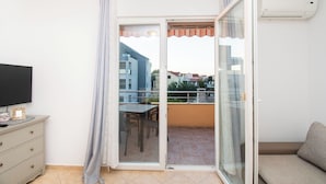 A balcony with a sliding glass door, a TV on a dresser, and a sofa. - Apartment Monika (Vodice)