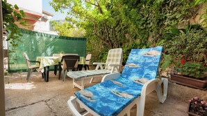 Un'area patio con mobili da esterno, tra cui un tavolo e sedie, e una poltrona prendisole con una stampa di delfini.