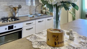 A kitchen with white cabinets, a stove, and a vase with white flowers on the counter. - Apartments Veli Rat (Sali)