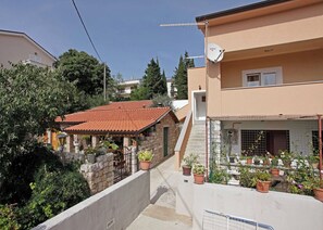 Un immeuble d’habitation avec un toit recouvert de tuiles rouges, une antenne parabolique et des plantes en pot.