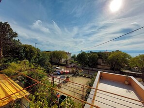A residential area with a view of the sea, a garden with potted plants, and a building with a tiled roof. - Apartments Toby (Novi Vinodolski)