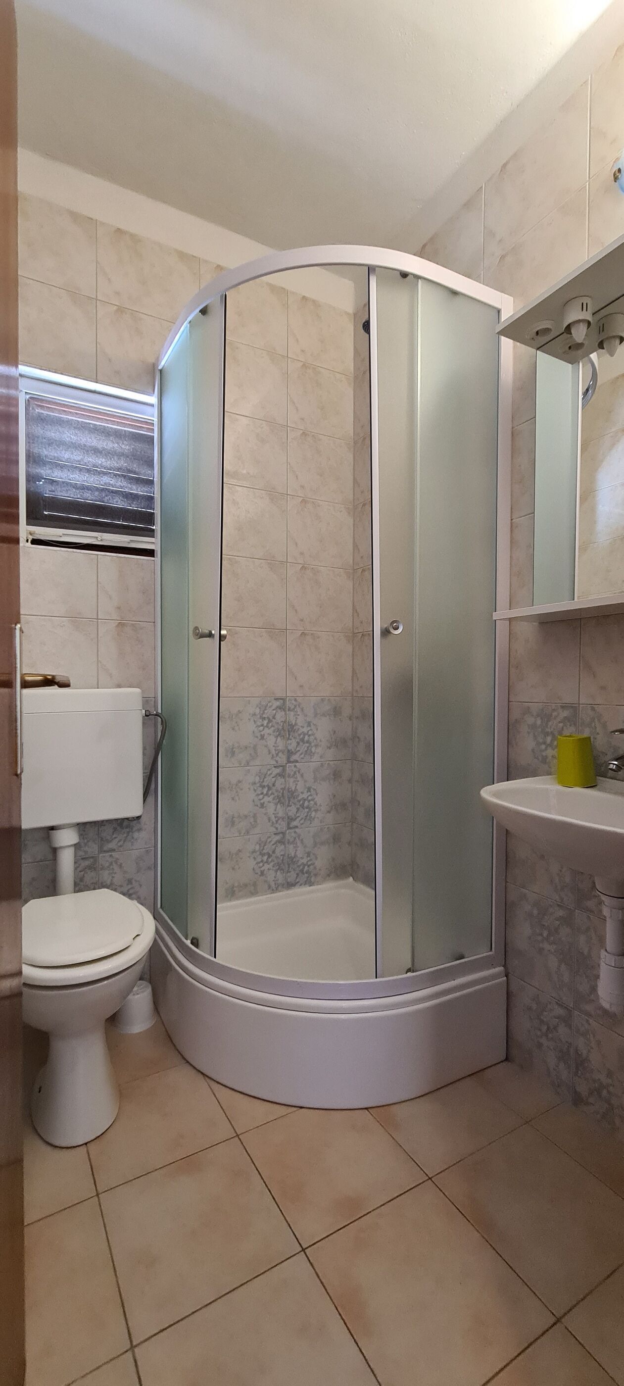 Un baño con ducha de vidrio, inodoro y lavamanos.