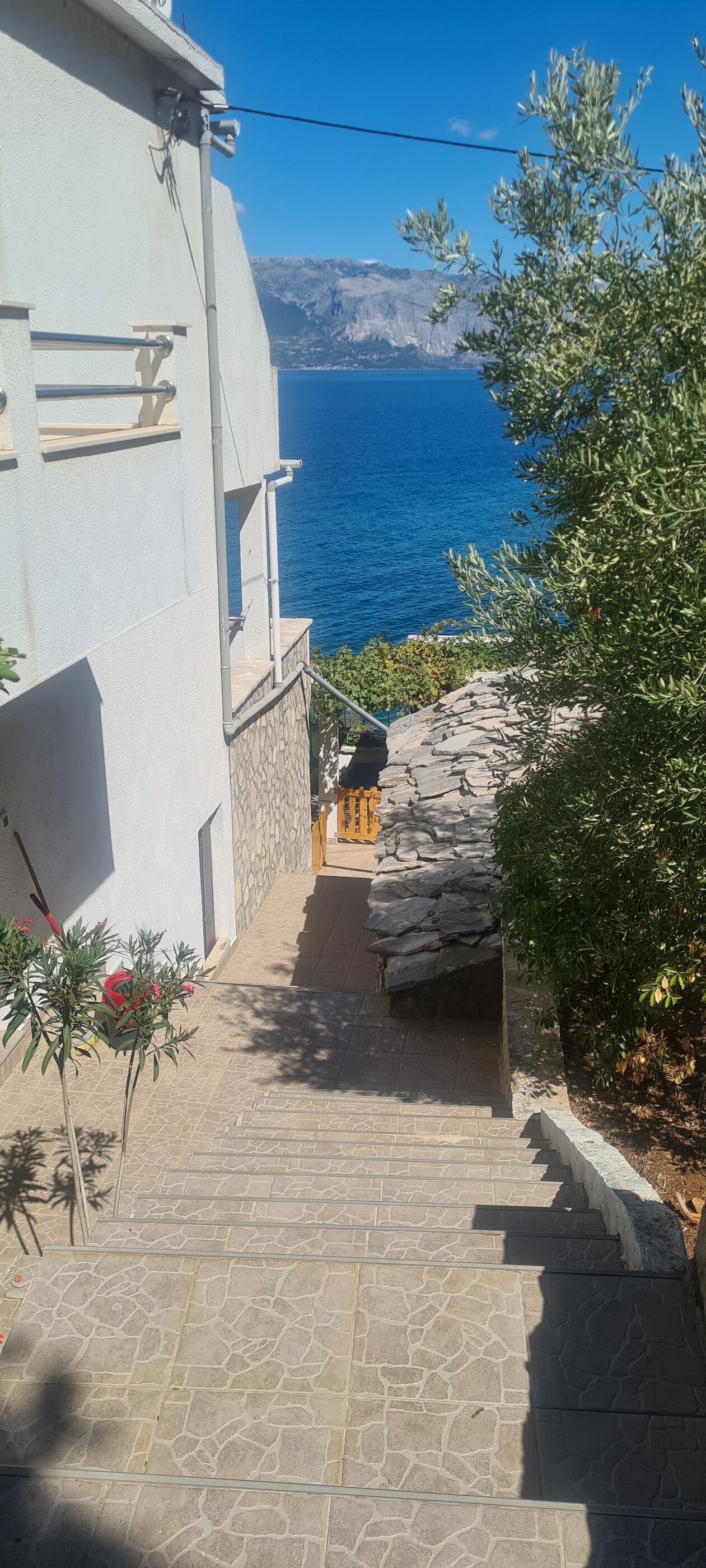 A stone staircase leading to a building with a view of the sea.