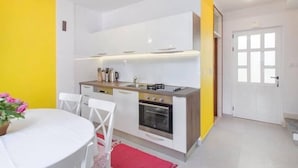 A compact kitchen with white cabinets, a gas stove, and a sink. - Apartment Burica (Primosten)