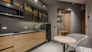 Cozinha moderna com micro-ondas embutido, geladeira de aço inoxidável e armários de madeira.