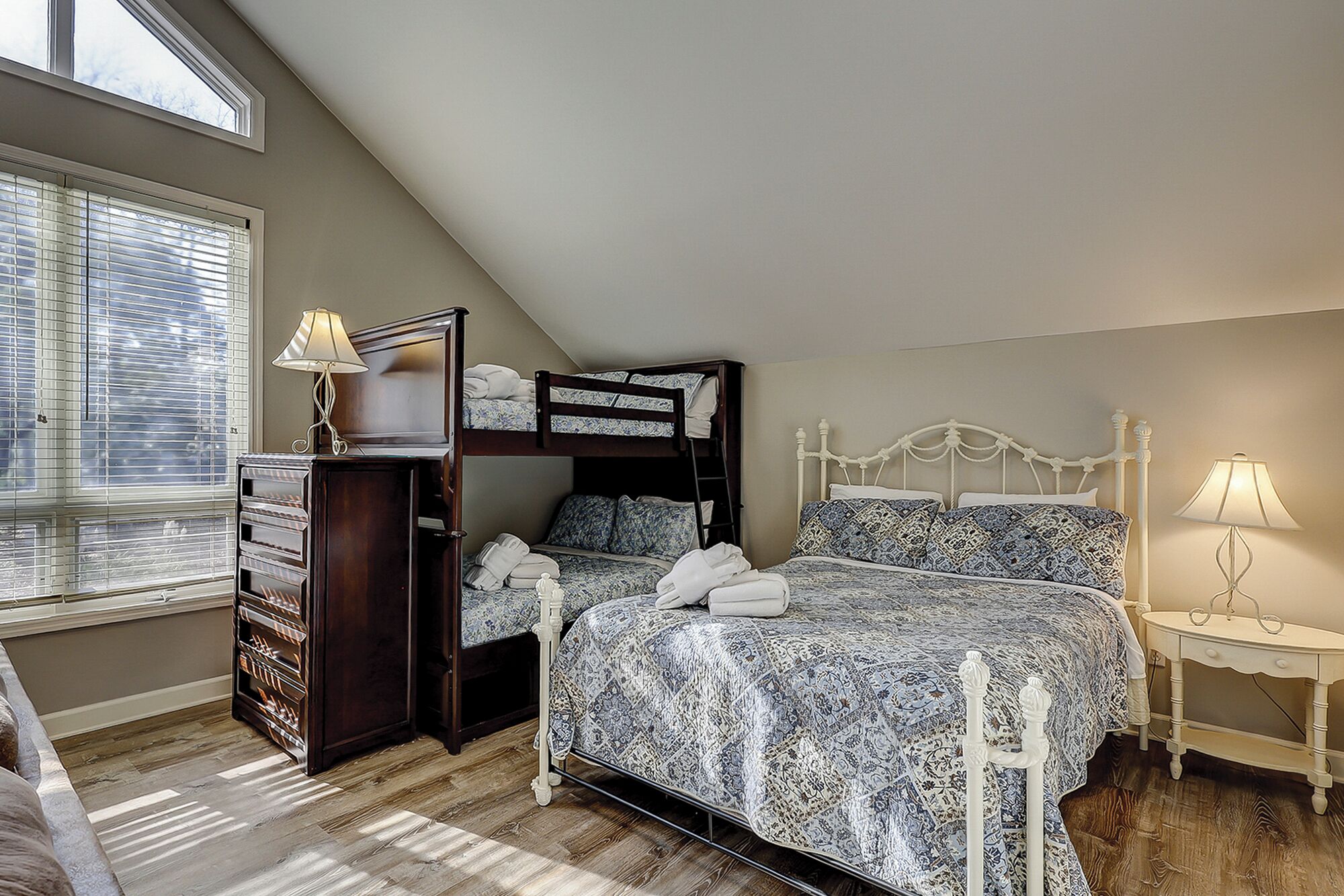 Een slaapkamer met een stapelbed, een dressoir, een nachtkastje en een lamp.