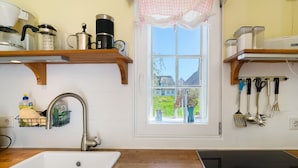 Cocina con un lavabo, encimera de madera y ventana con vistas a la vegetación.