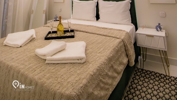 Una habitación de hotel con una cama grande, una mesita de noche, un espejo y un candelabro.