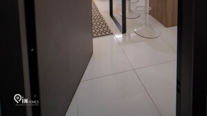 Una cocina moderna con encimeras blancas, un espejo redondo y un comedor con sillas blancas.