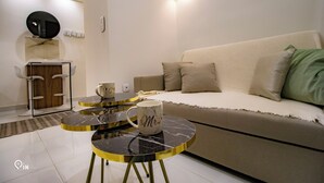 Una sala de estar moderna con un sofá, dos mesitas auxiliares, una mesa de centro y un espejo decorativo.