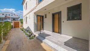 A modern building with a stone facade, large windows, and a paved walkway. - Kalender Pansiyon Fethiye (Fethiye)